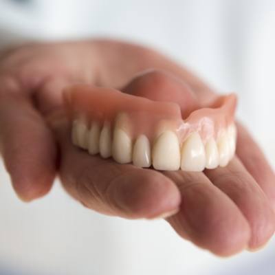 Person holding a full upper denture