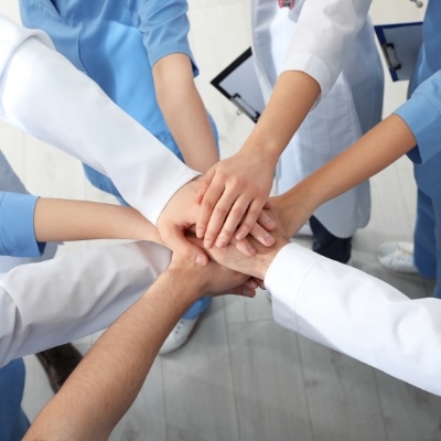 Group of dental team members placing their hands together in circle