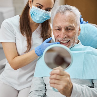 patient smiling while looking in dental mirror 