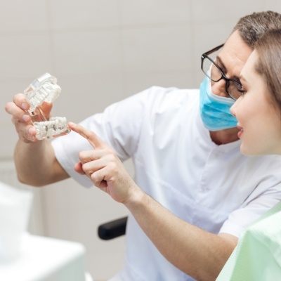 Dentist showing a patient a model of a dental implant