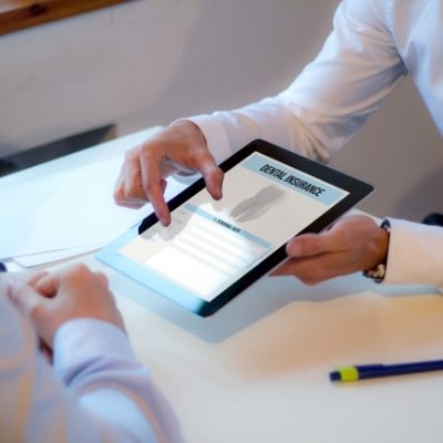 Two people looking at dental insurance information on a tablet screen