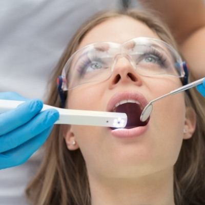 Woman having her mouth examined by dentist using intraoral camera