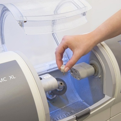 Person placing a ceramic block into a CEREC one visit dental crown machine