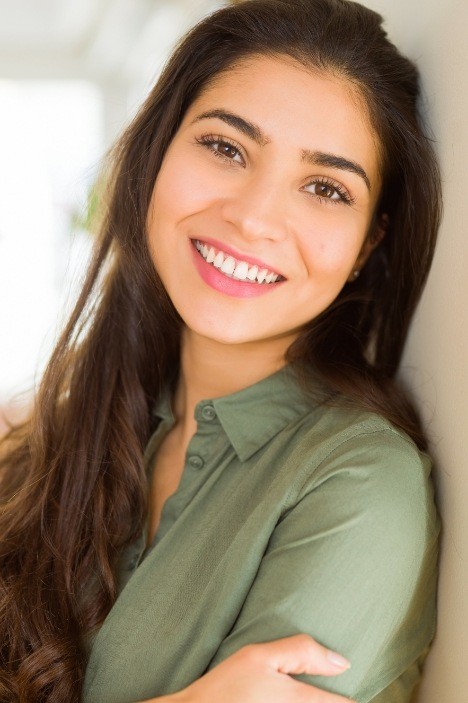 Young woman in green shirt smiling after preventive dentistry in Millis