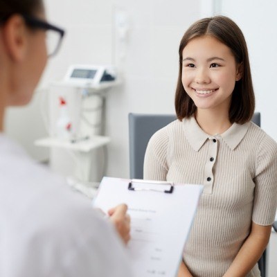 Woman smiling while her dentist writes on clipboard