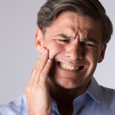 Man holding the side of his face in pain