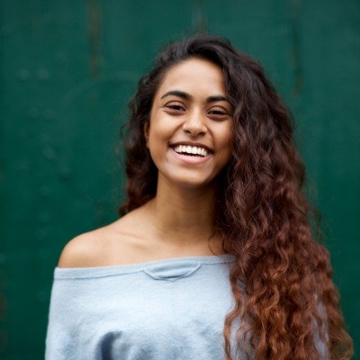 Young woman with curly brown hair grinning