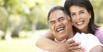 Smiling man and woman hugging outdoors